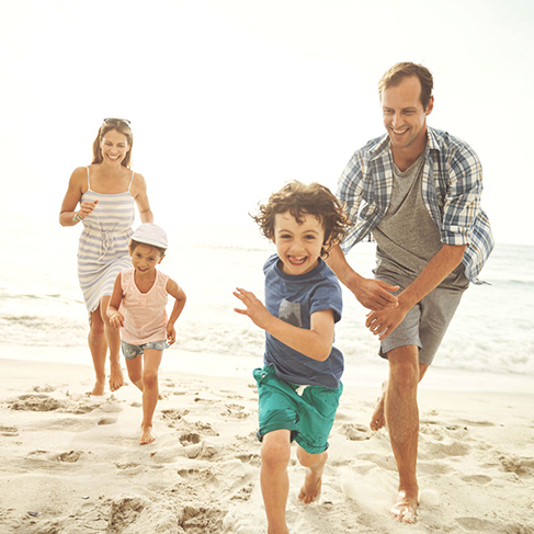 Photo d’une famille de quatre personnes qui courent sur la plage
