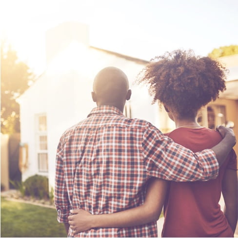 Photo représentant un couple de dos face à une maison 